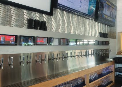 Installed Pourtek Beverage Wall: 10.1-inch screens above faucet pairs on a stainless drip tray